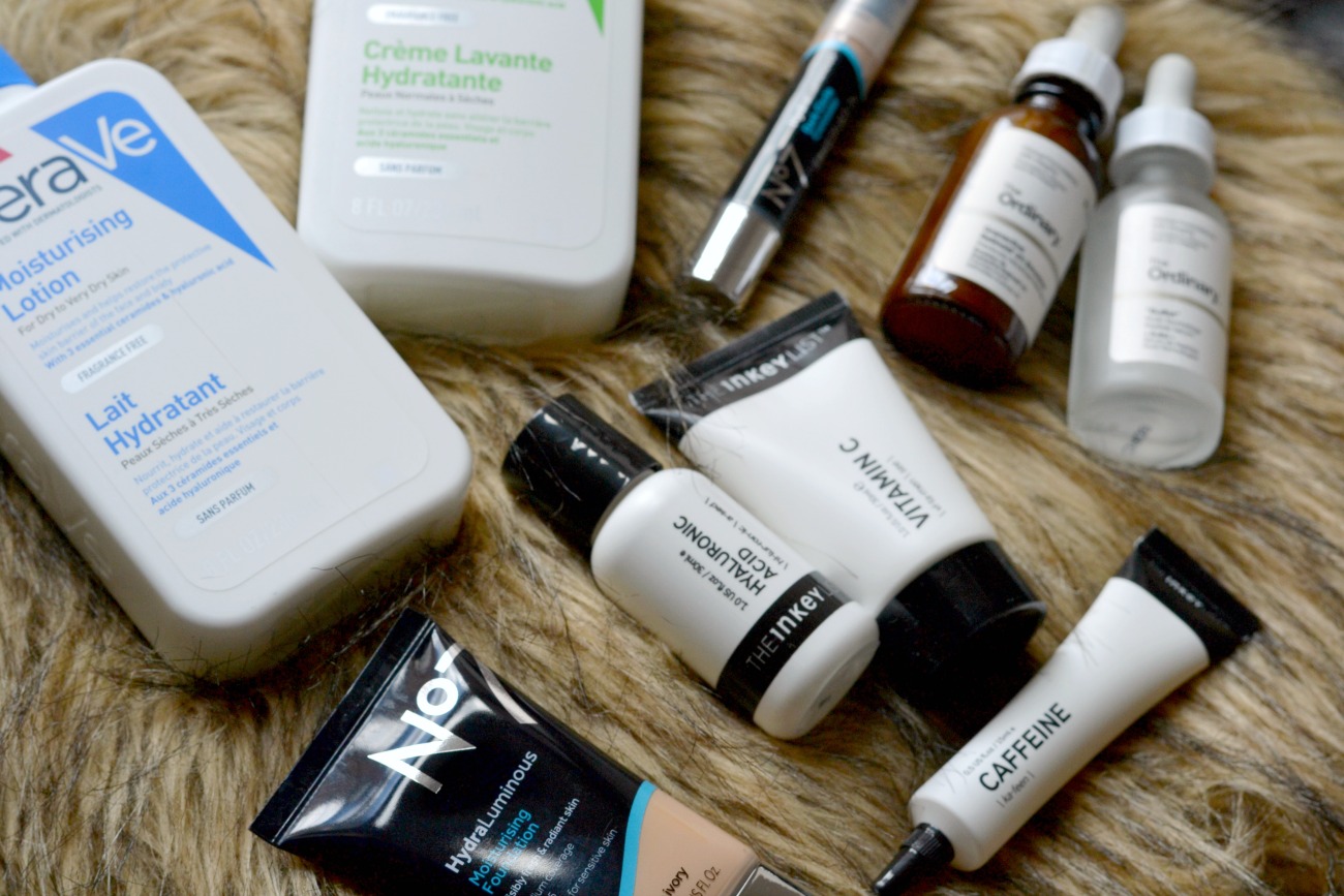 skincare and makeup products bu Cerave, Inkey List and No.7 laid out on fluffy cushion